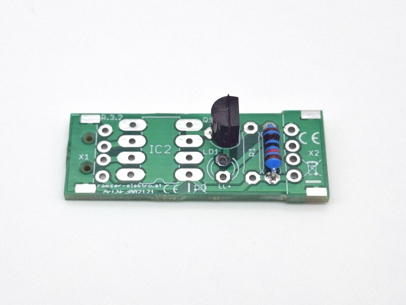 Grüne Leiterplatte mit verschiedenen Bauteilen, einschließlich eines Widerstands und eines Transistors.